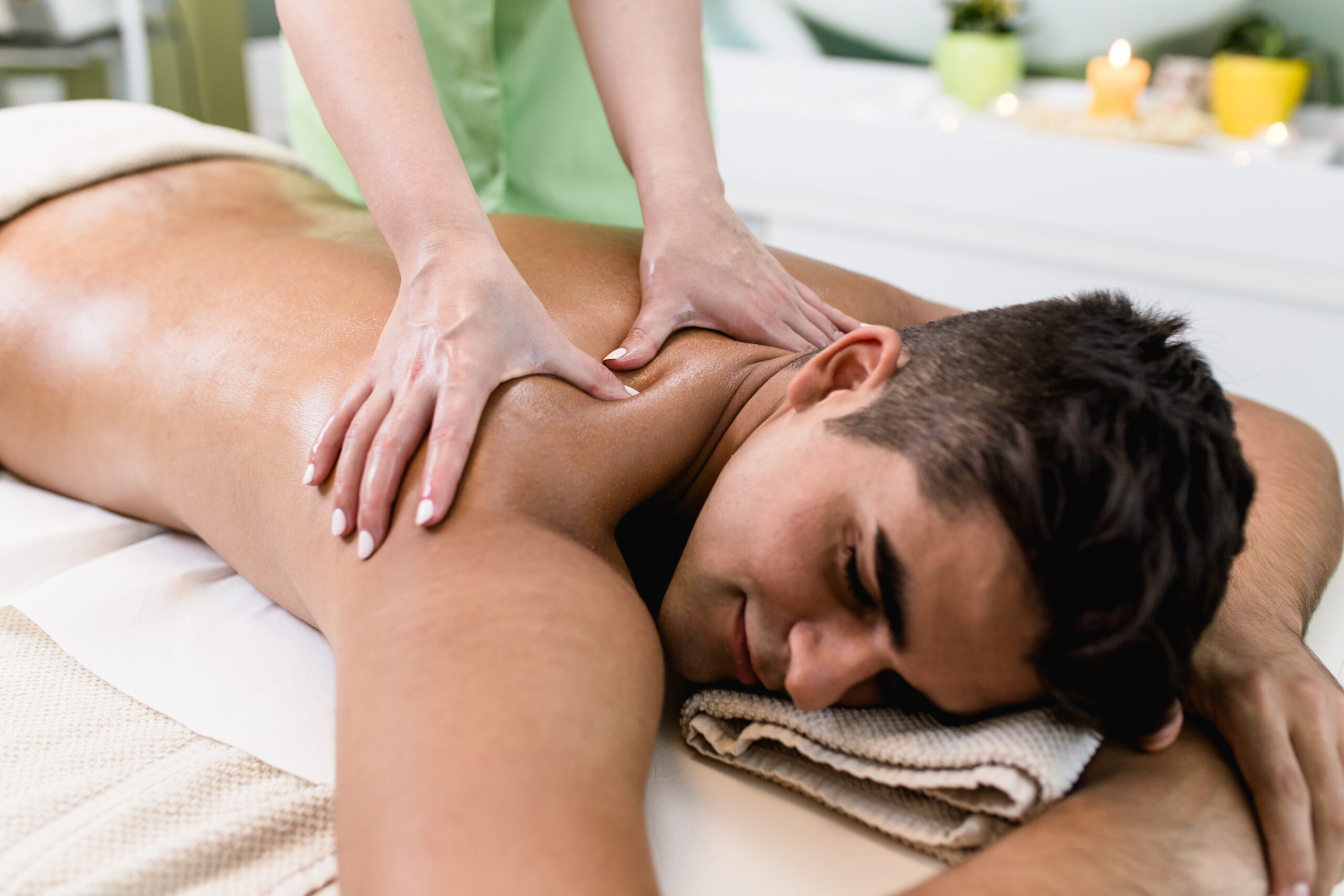 Good looking young man enjoying in massage in the spa salon.