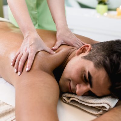 Good looking young man enjoying in massage in the spa salon.